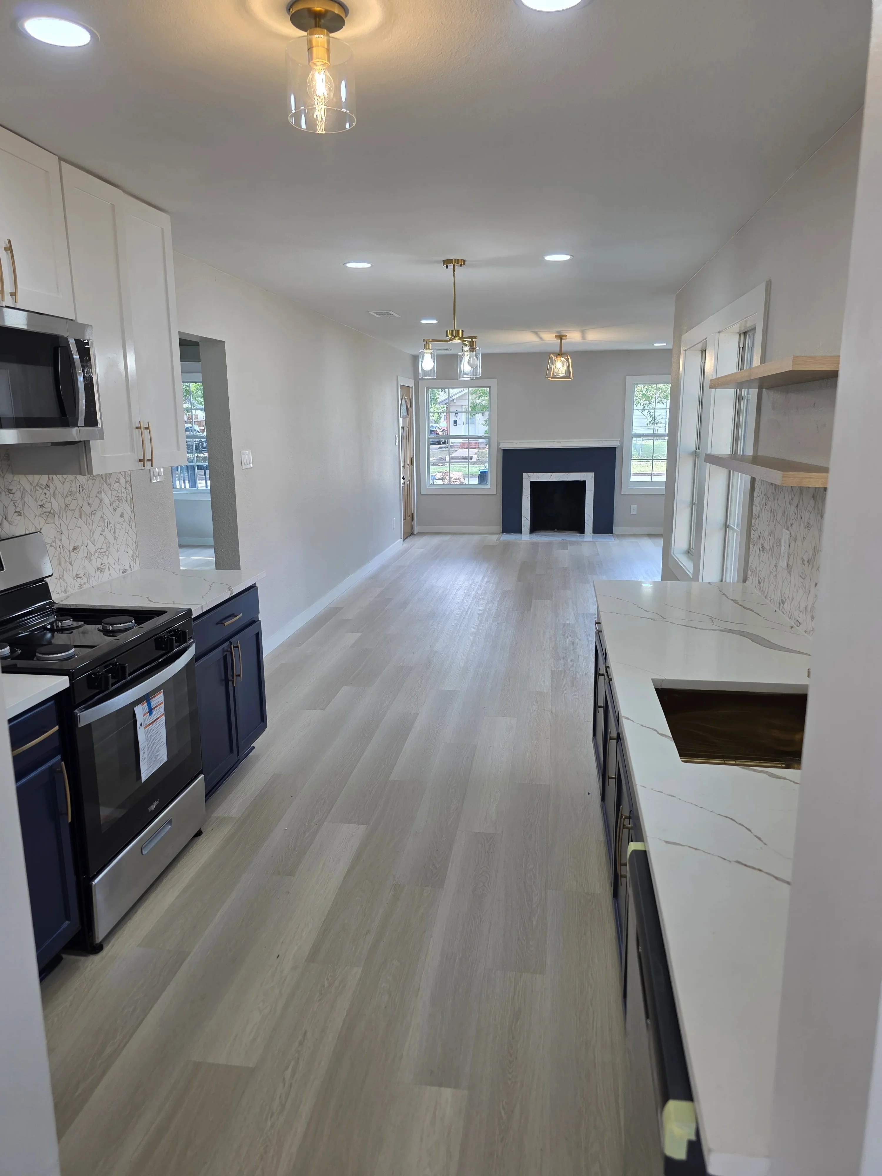 Modern kitchen with recessed and pendant lighting, white cabinets, marble backsplash, stainless steel appliances