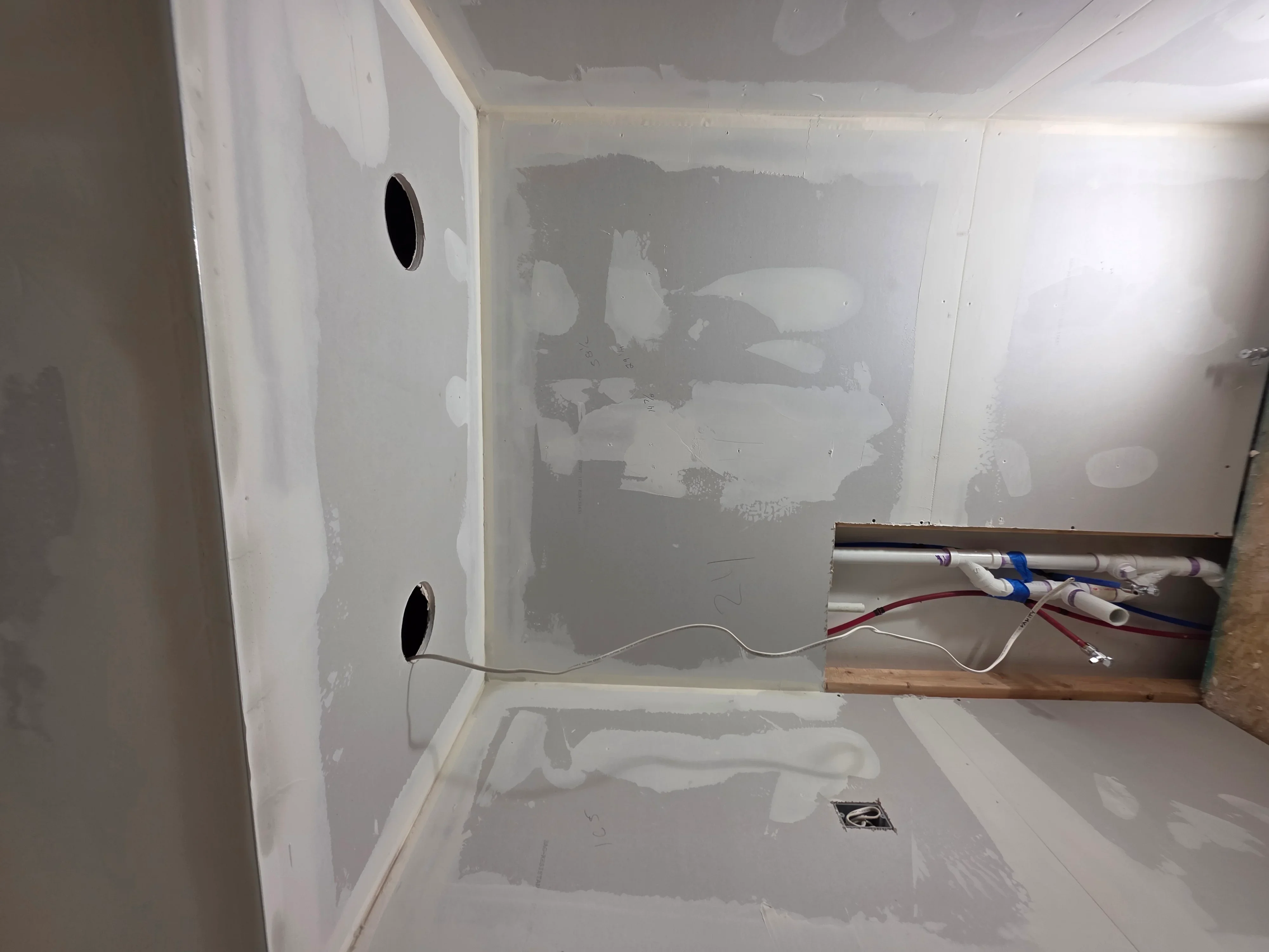 Electrical rough-in with outlet boxes, knockout holes, and organized color-coded wiring on drywall framing