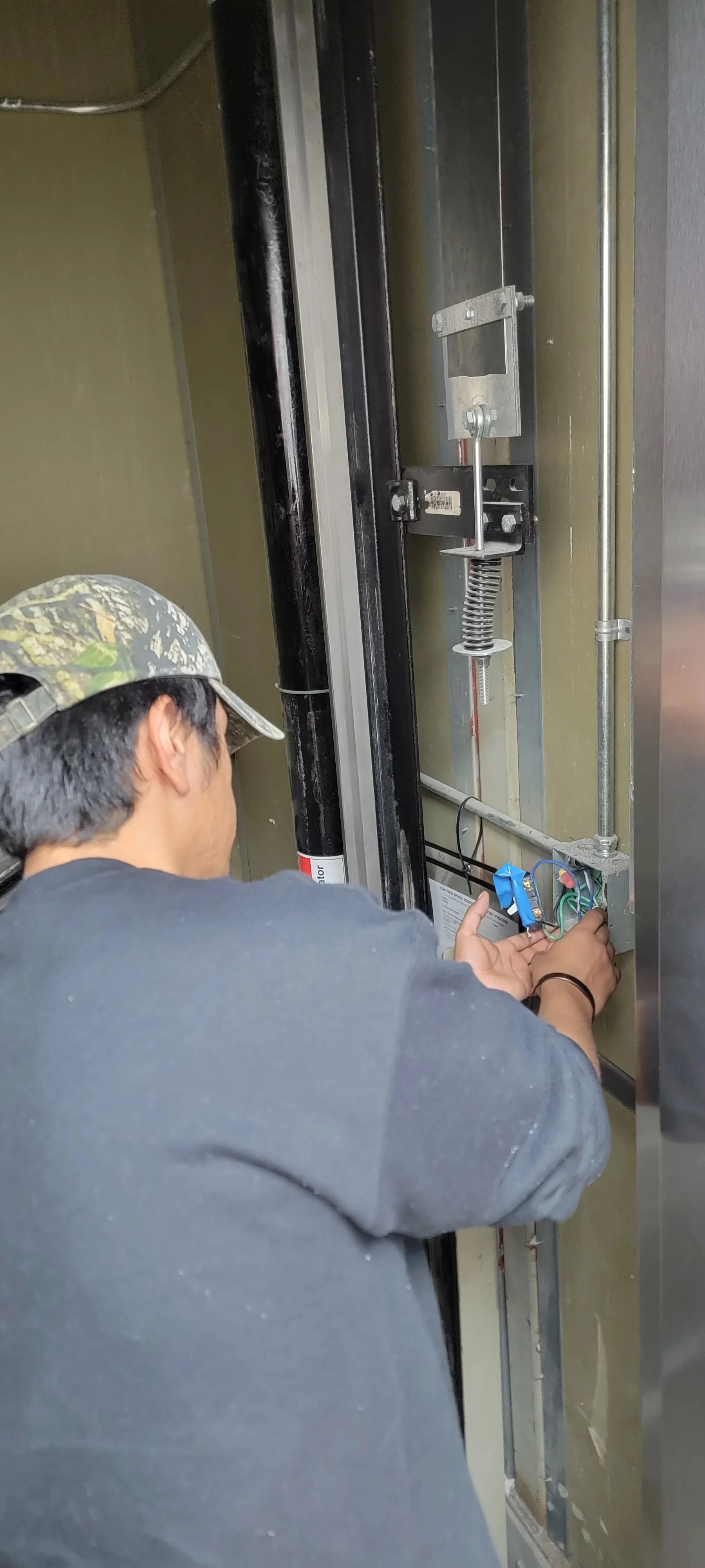 Technician installing garage door opener motor unit with electrical wiring connections