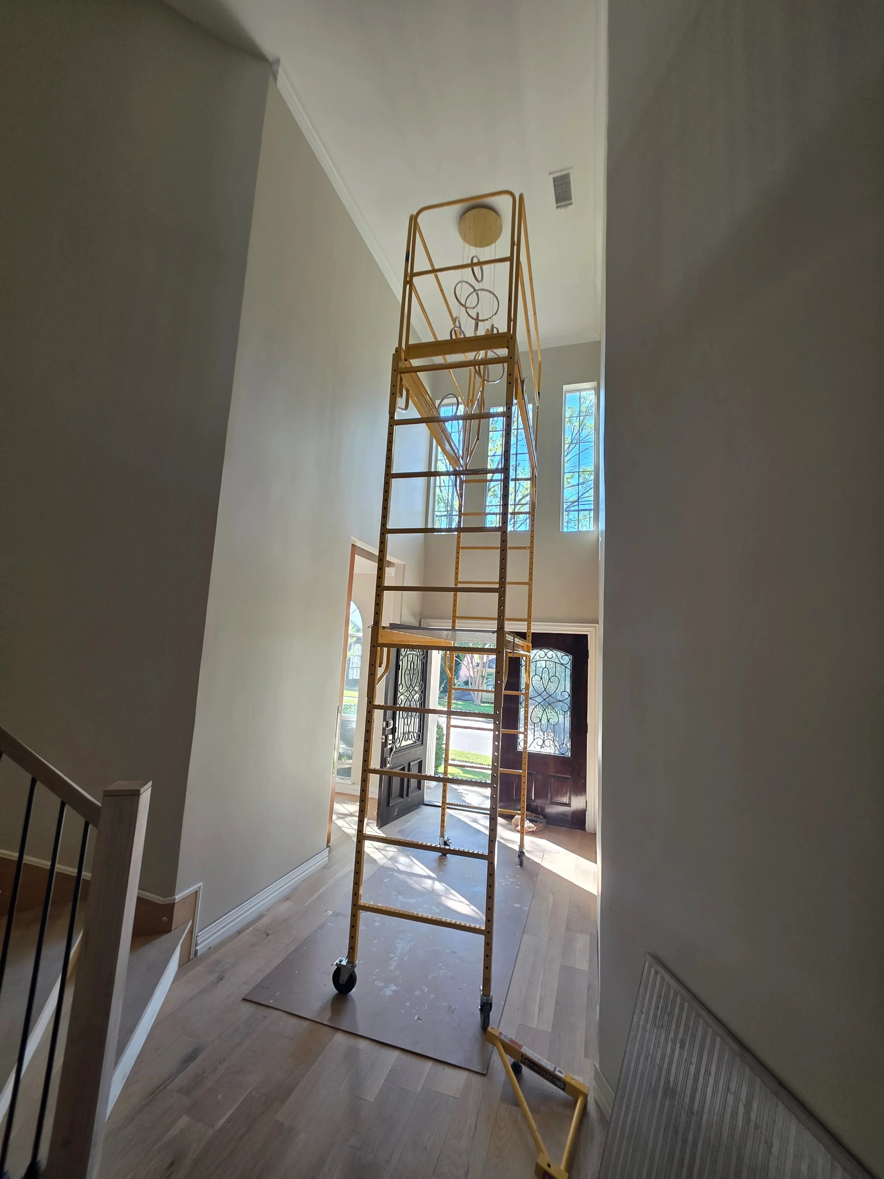 Tall metal scaffolding in foyer with white walls and upper electrical outlet installation
