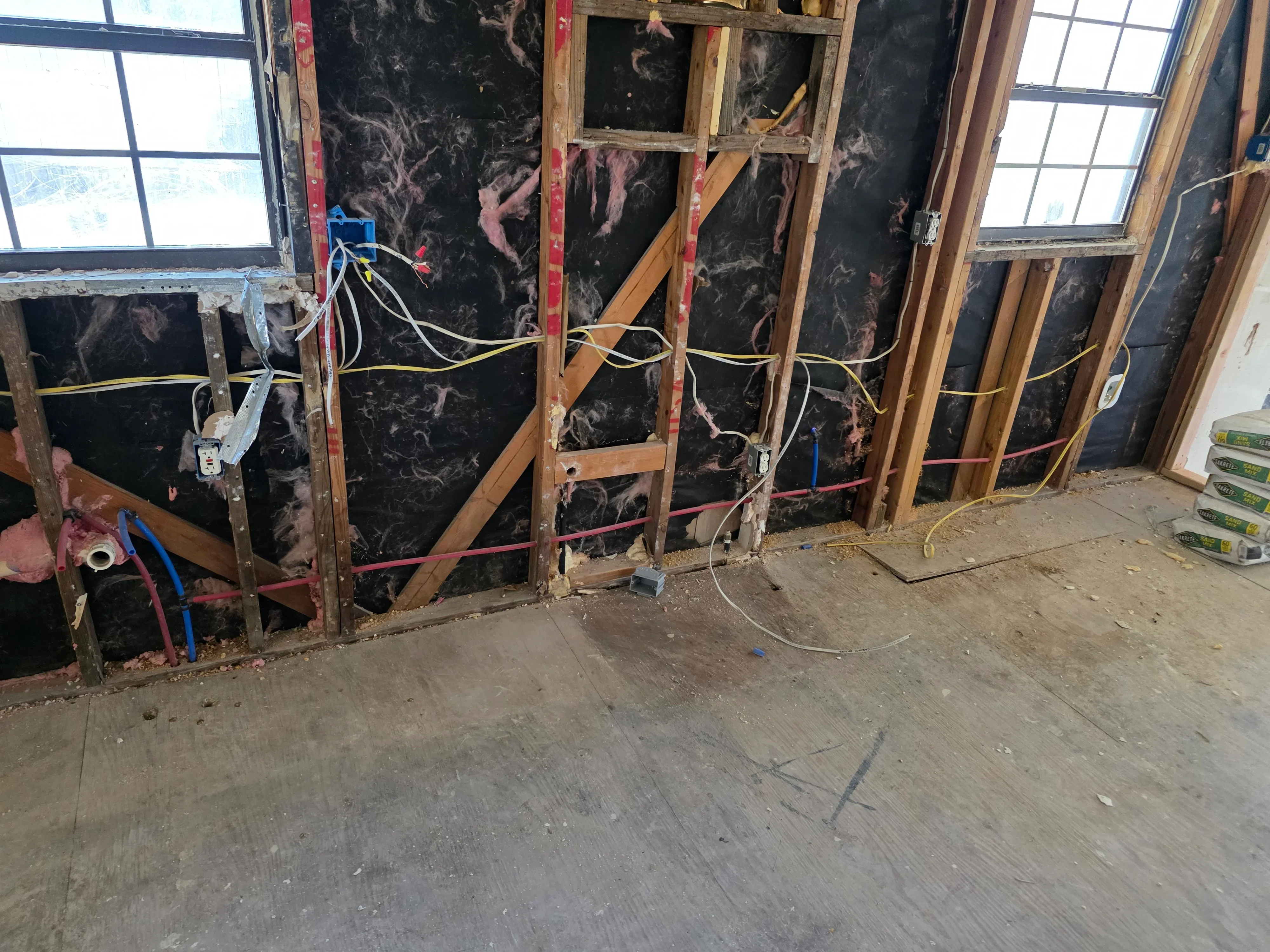 Electrical rough-in with Romex wiring, junction boxes, and outlet boxes installed in wooden wall framing