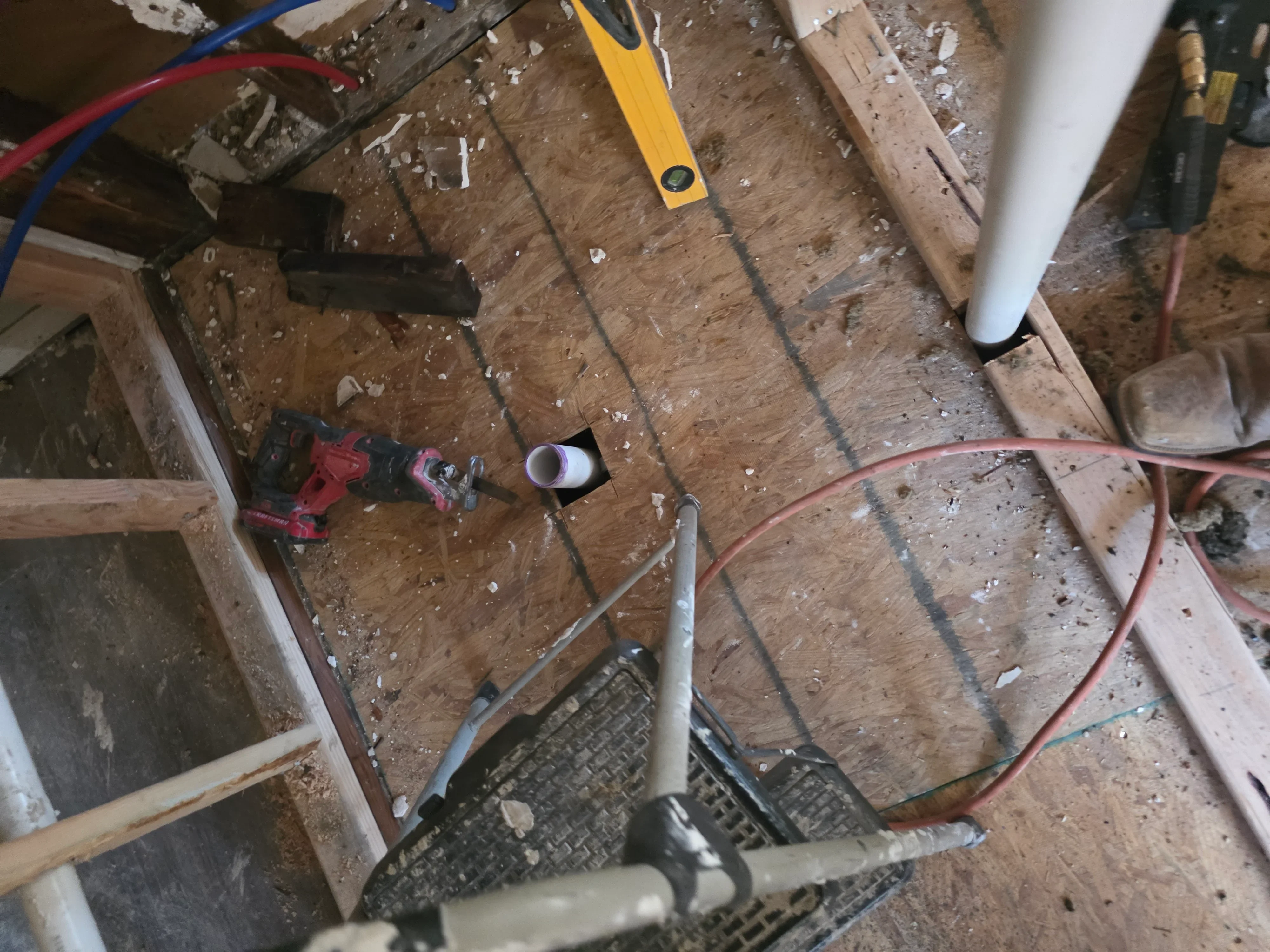Electrical conduit, colored wiring, and junction boxes installed on wooden subfloor framing