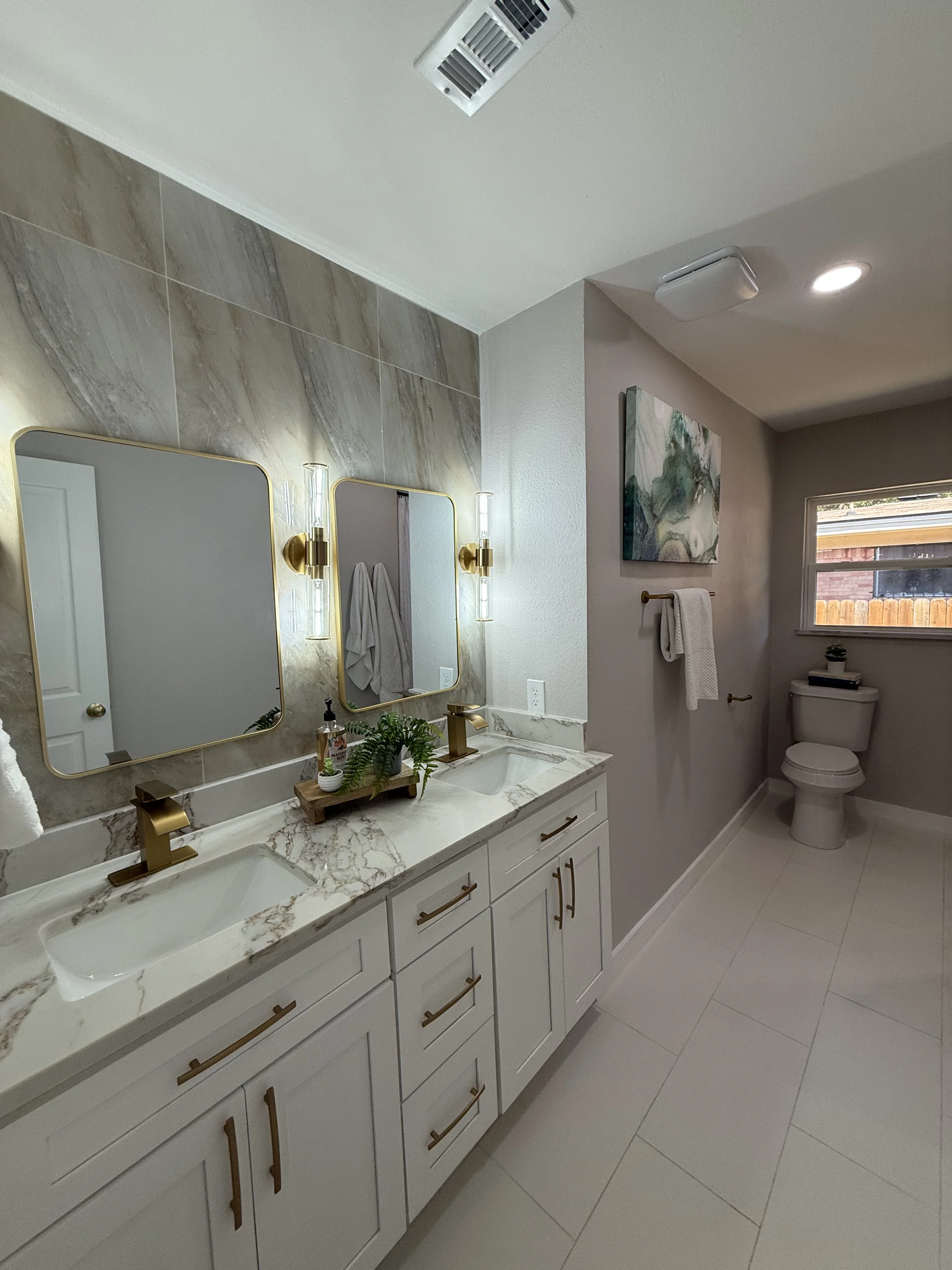Master bathroom with dual brass sconces, recessed lighting, marble backsplash, white vanity cabinetry