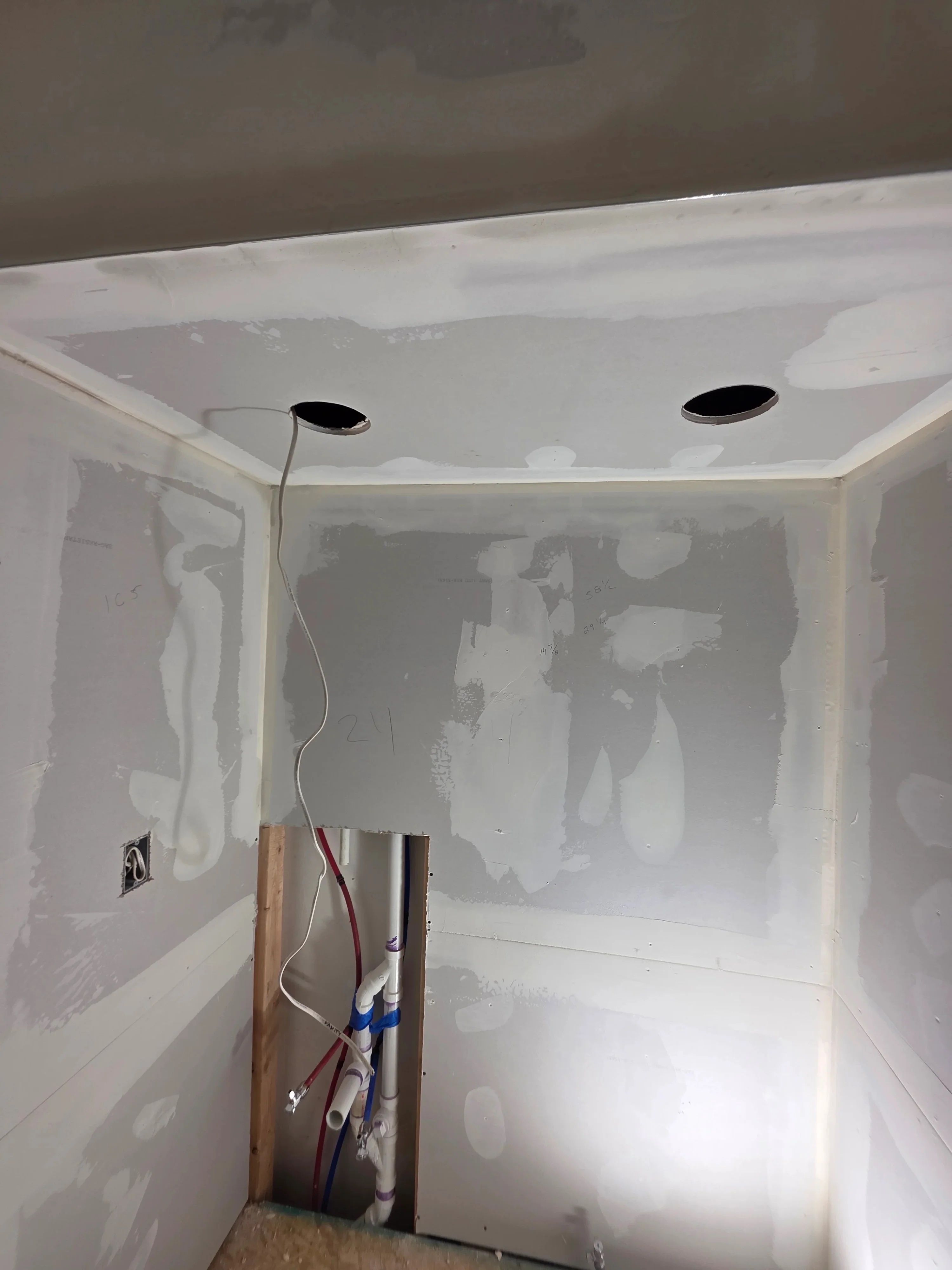 Recessed light fixtures installed in drywall ceiling with electrical wiring and trim rings