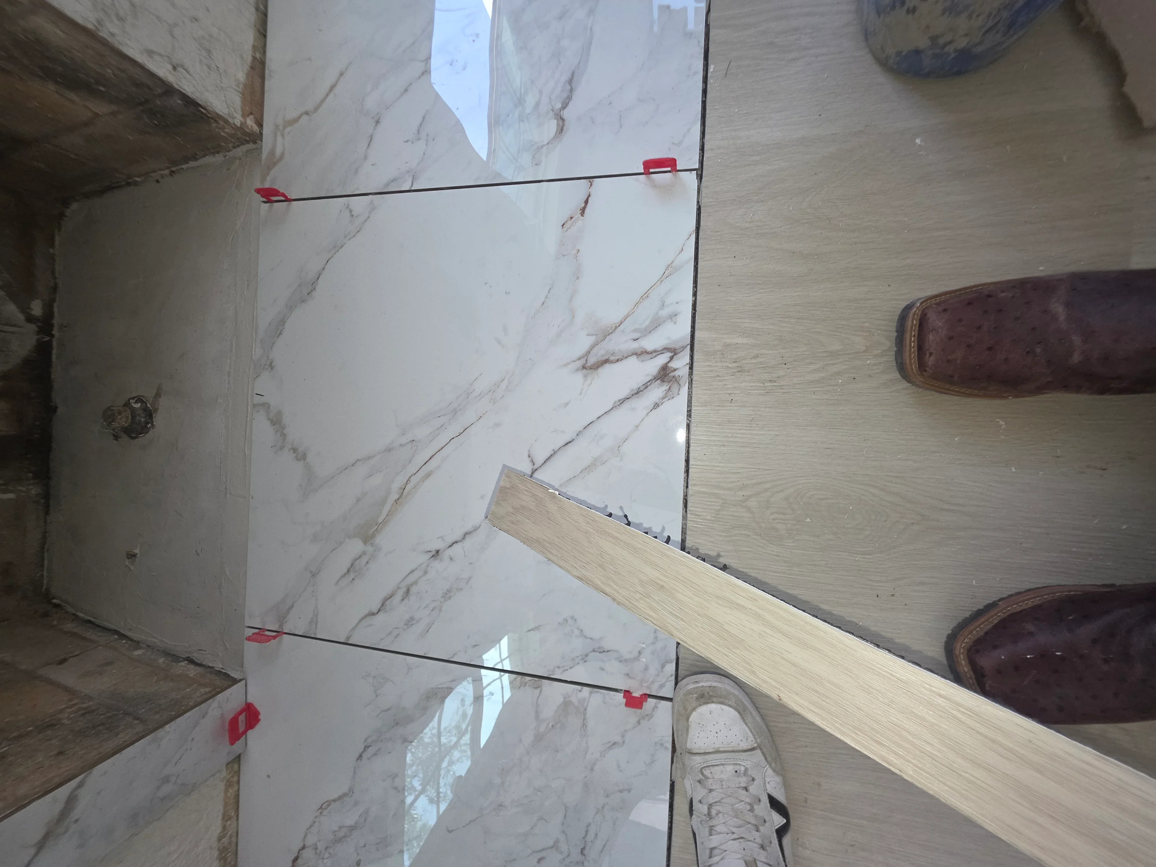 Marble tile flooring with electrical conduit and red wire clips installed in preparation