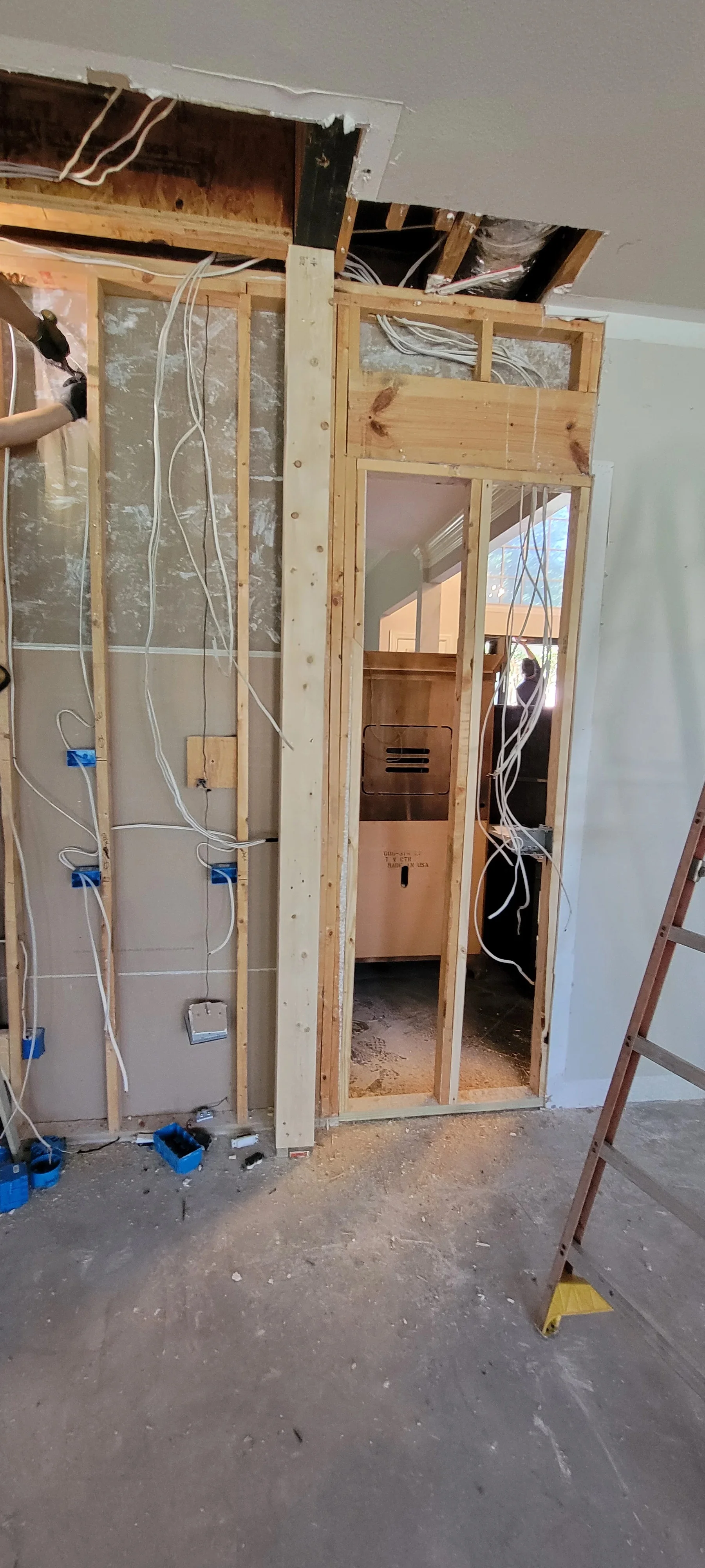 Electrical rough-in with white Romex wiring, blue connectors, and junction boxes in wooden stud framing