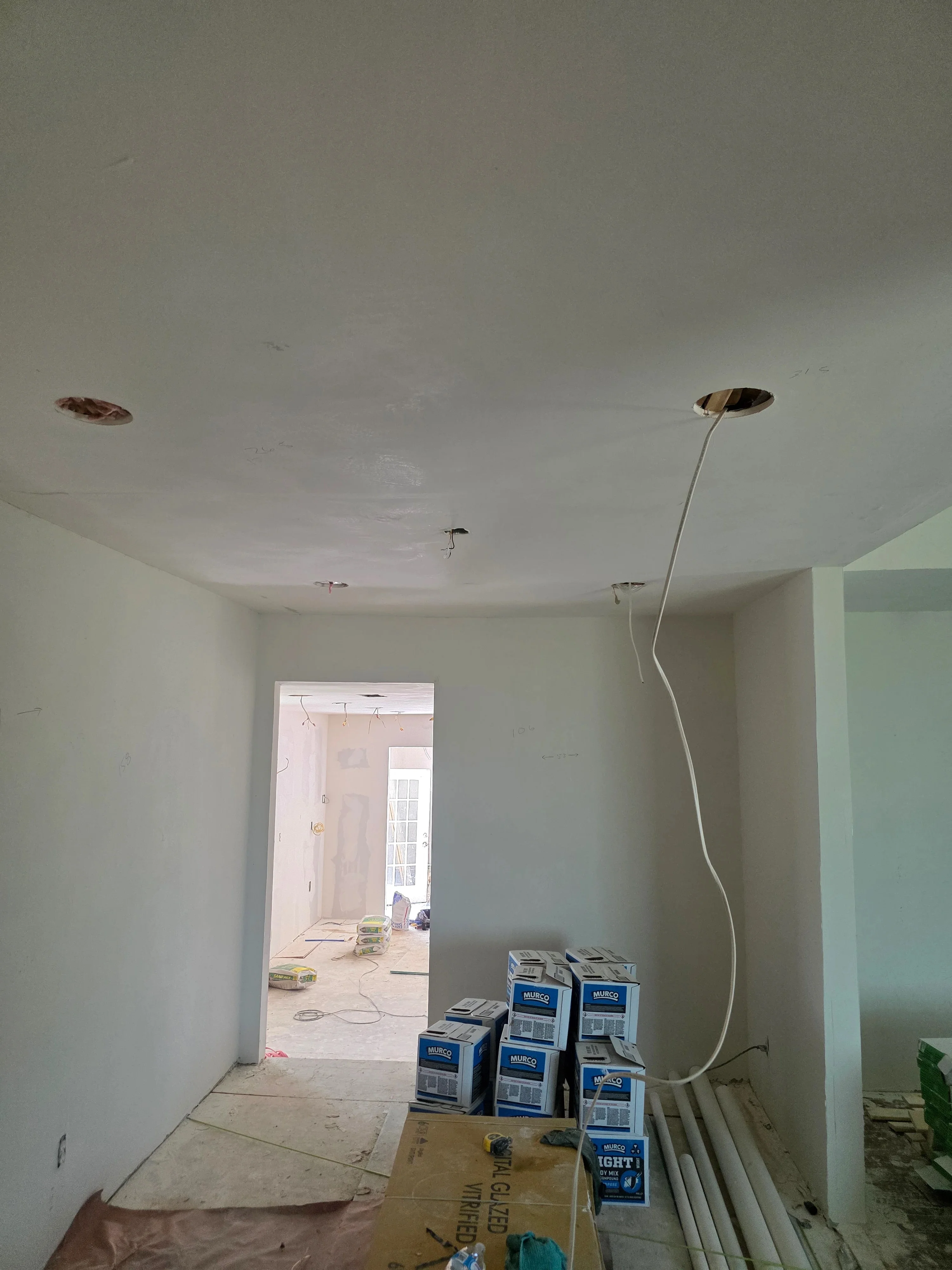 Drywall ceiling with recessed lighting fixtures, electrical wiring, and outlet boxes during rough-in phase