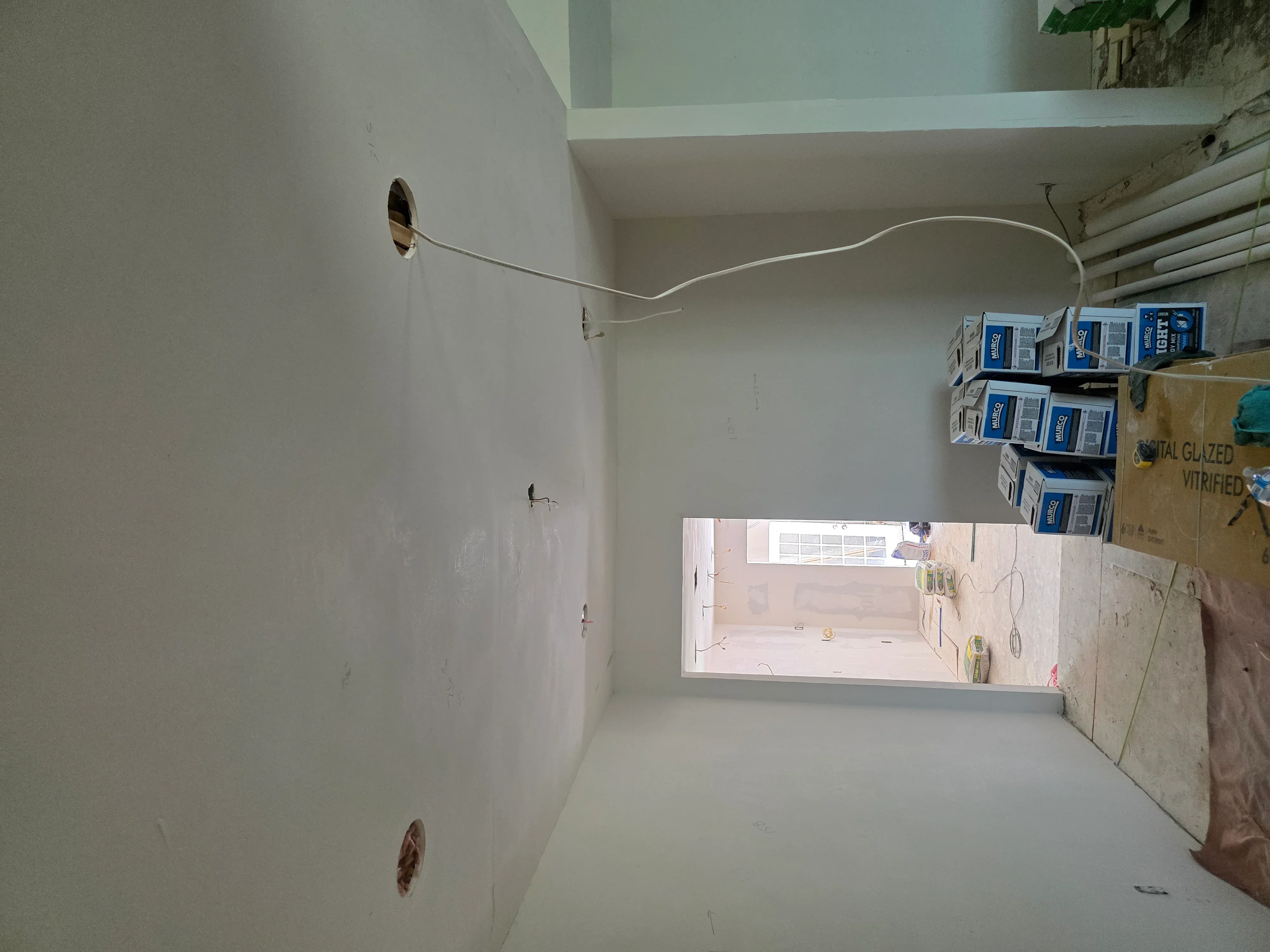 Electrical rough-in with outlet boxes, conduit, and wiring in drywall-ready room