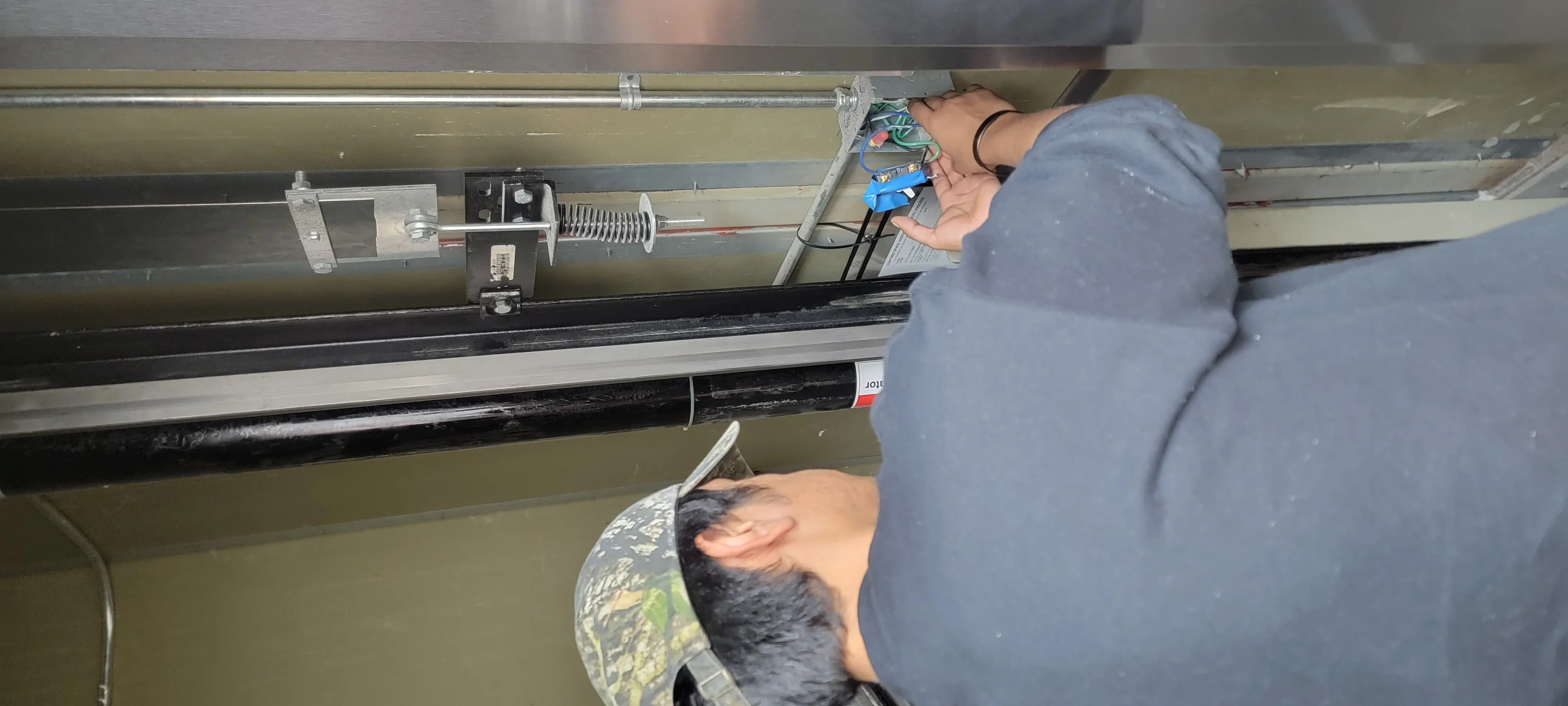 Technician installing garage door opener motor and electrical components on ceiling track