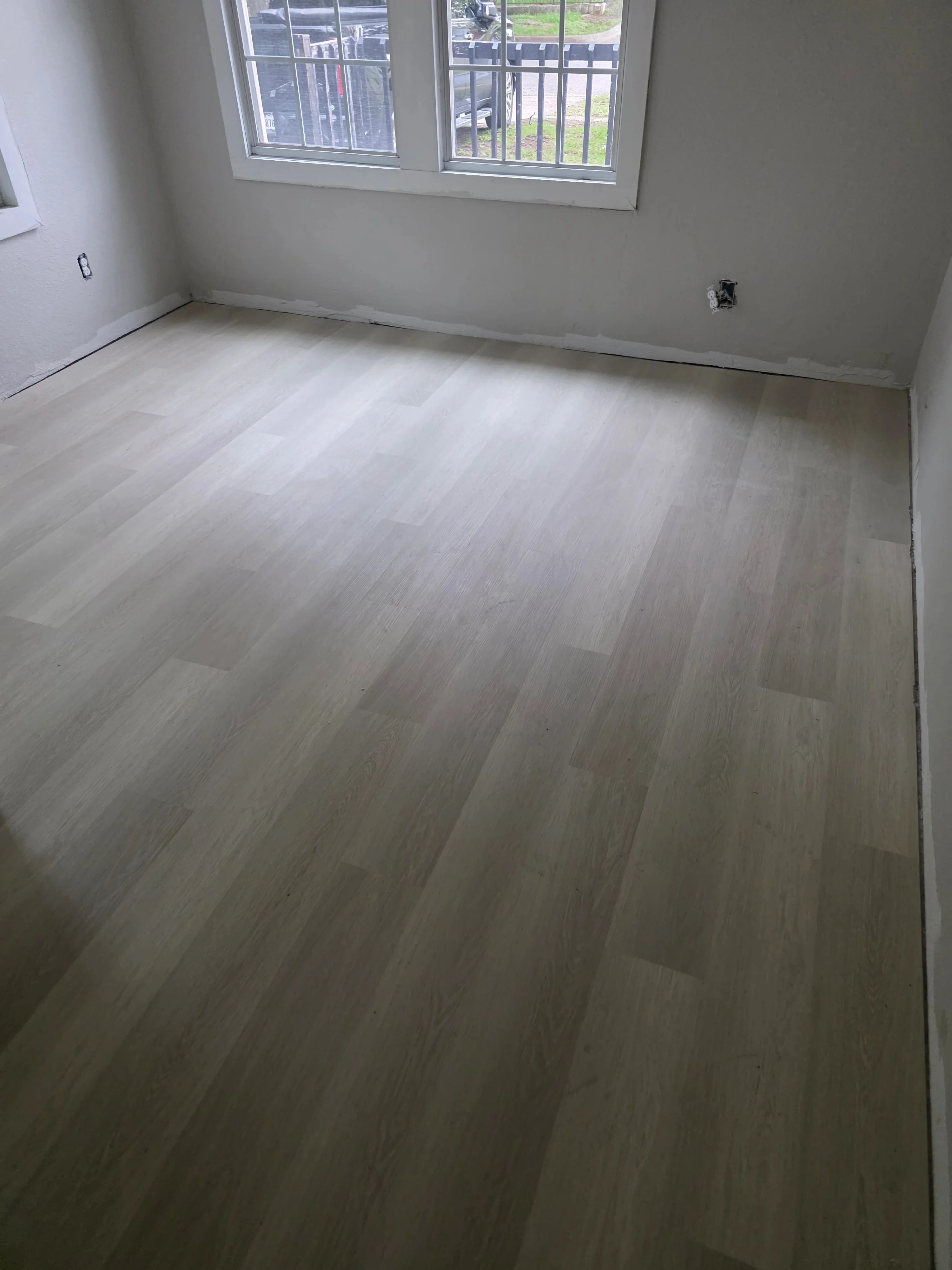 Light gray luxury vinyl plank flooring in diagonal pattern, drywall walls, new electrical outlet
