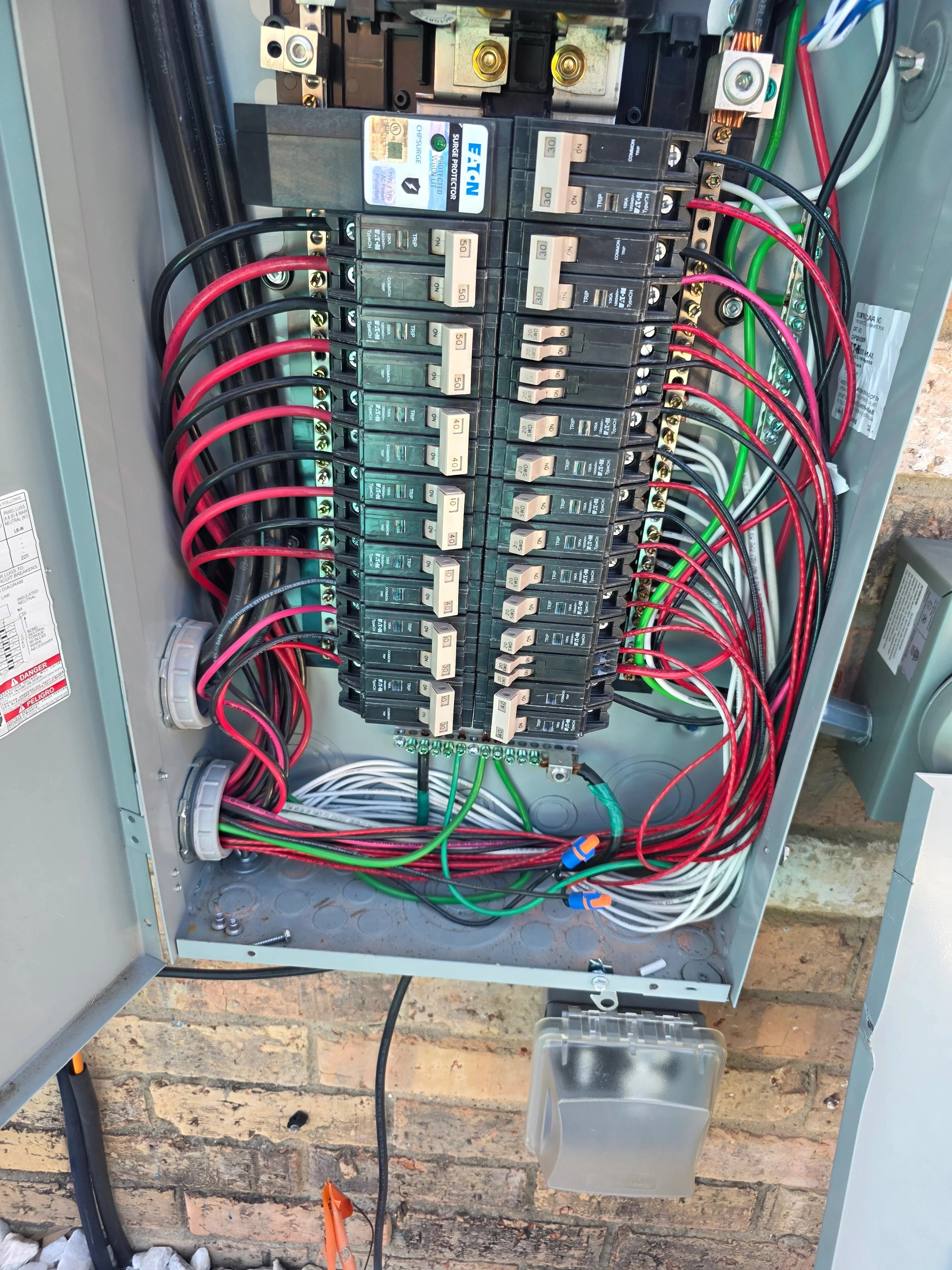 Main electrical panel with dual-pole breakers, red and green wiring, organized cable management