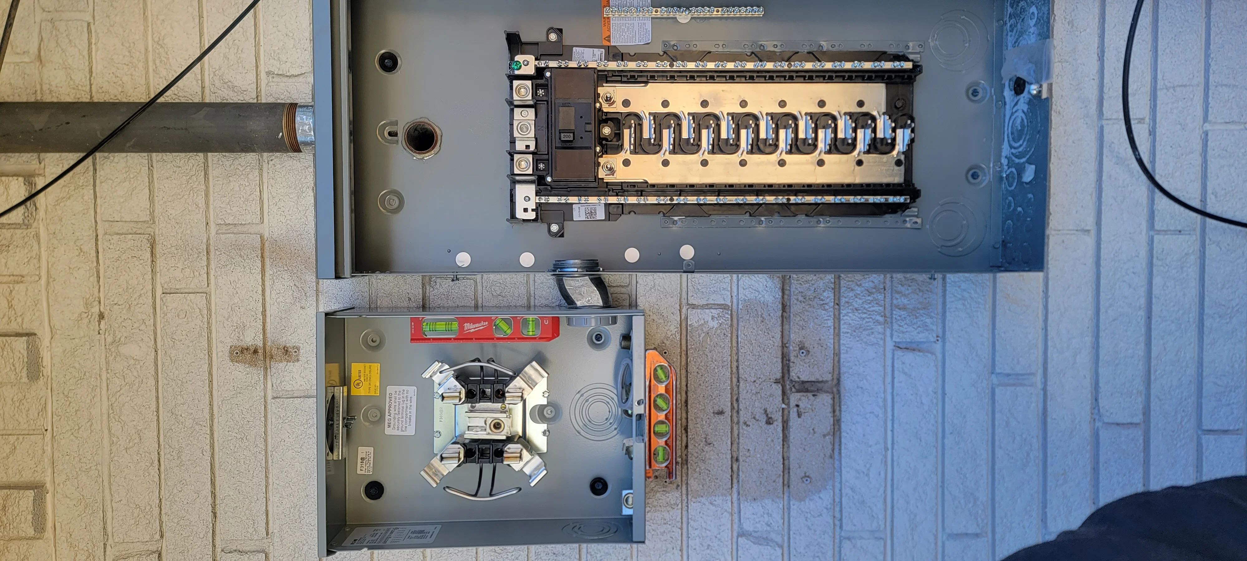 Electrical panel with breakers, sub-panel, and branch circuits installed on masonry wall