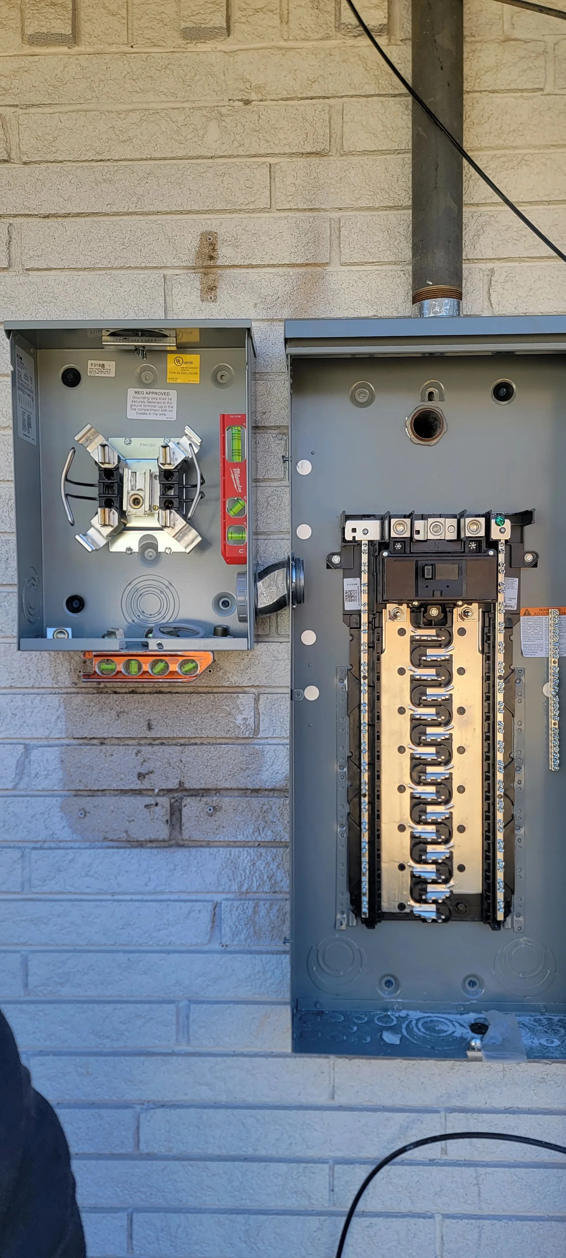 Electrical panel upgrade with main disconnect and breaker panel on brick wall