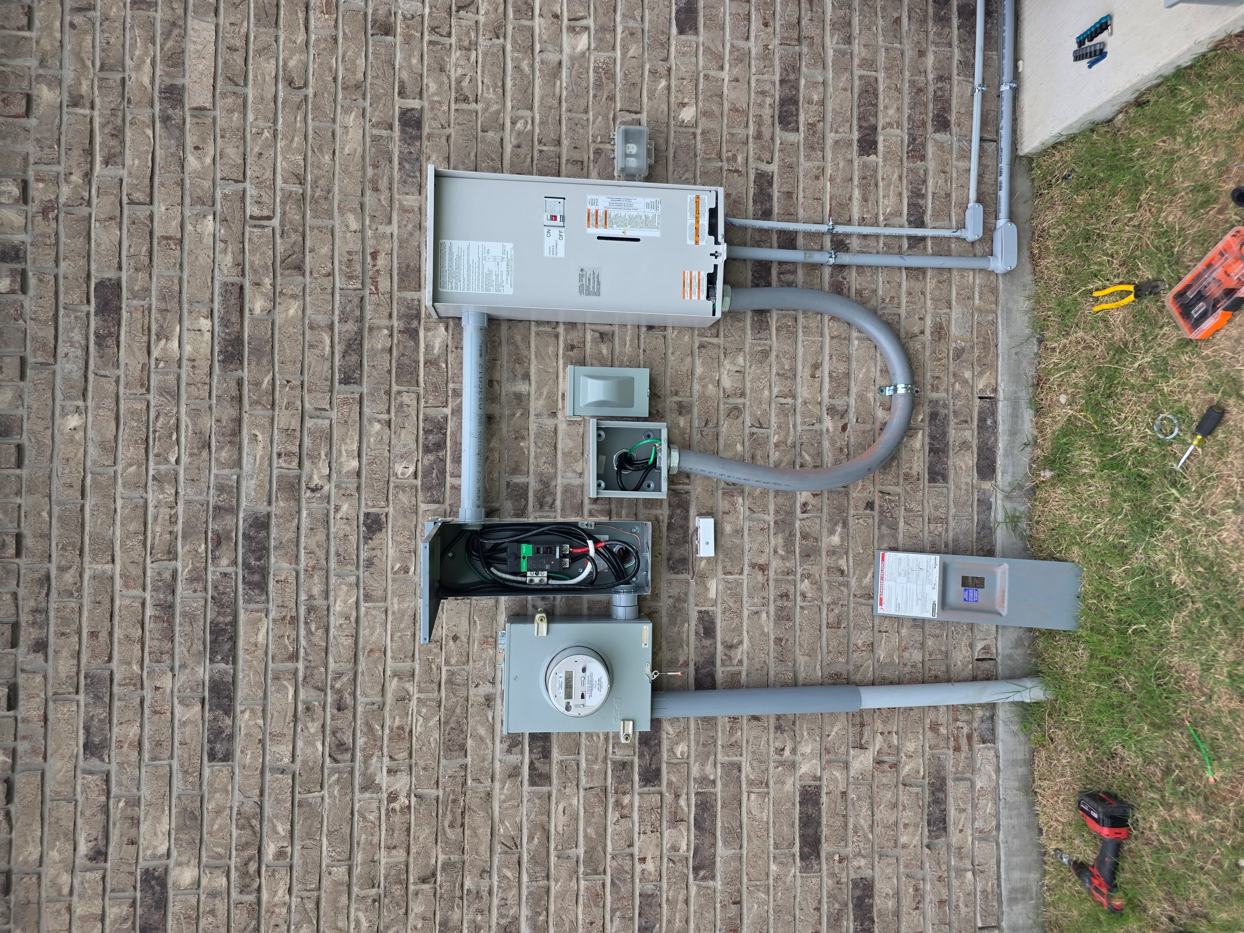 New electrical panel, meter, and conduit installation on brick foundation with organized wiring