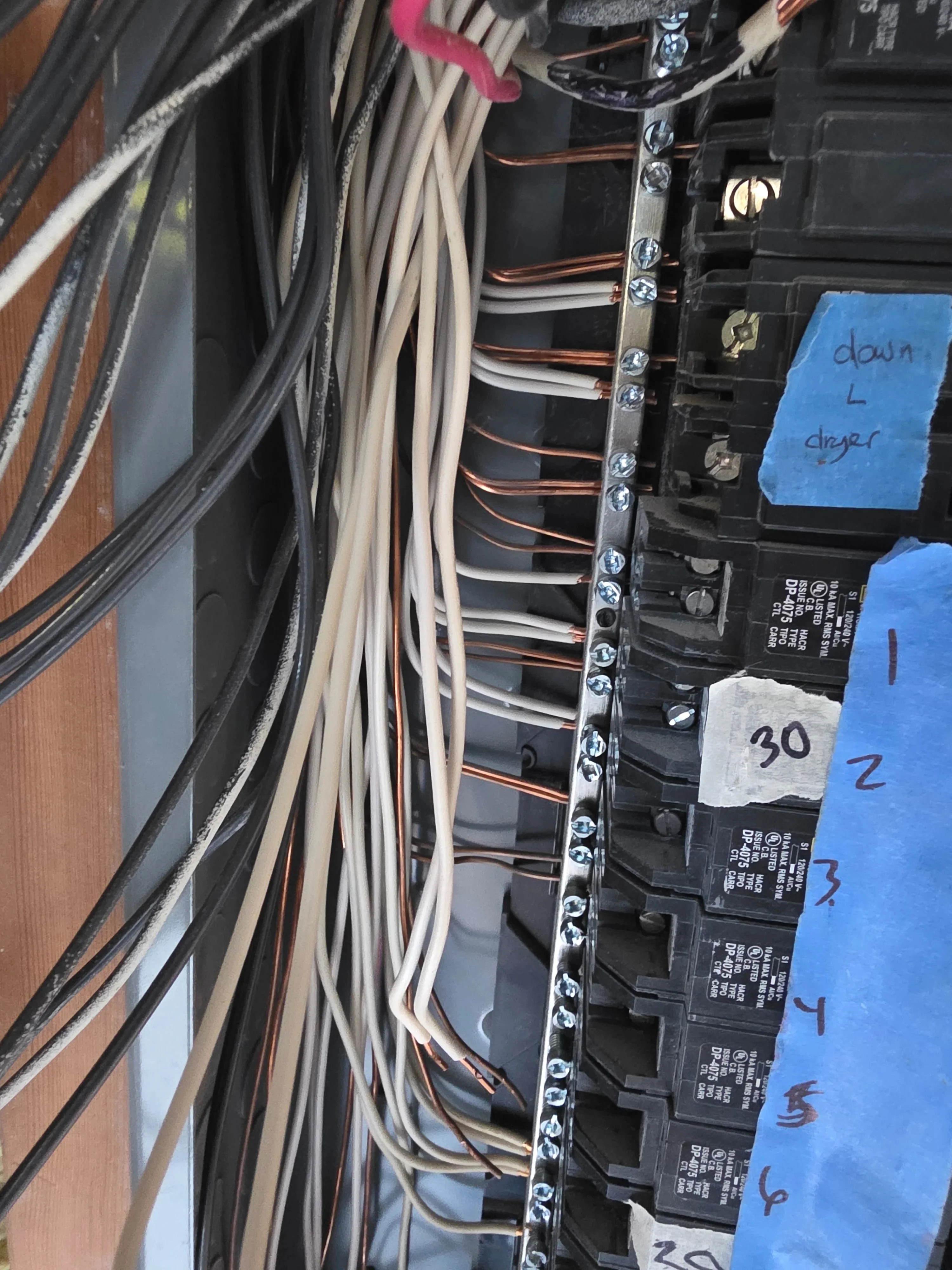 Electrical panel with new breakers, organized copper and white wiring, and labeled circuits