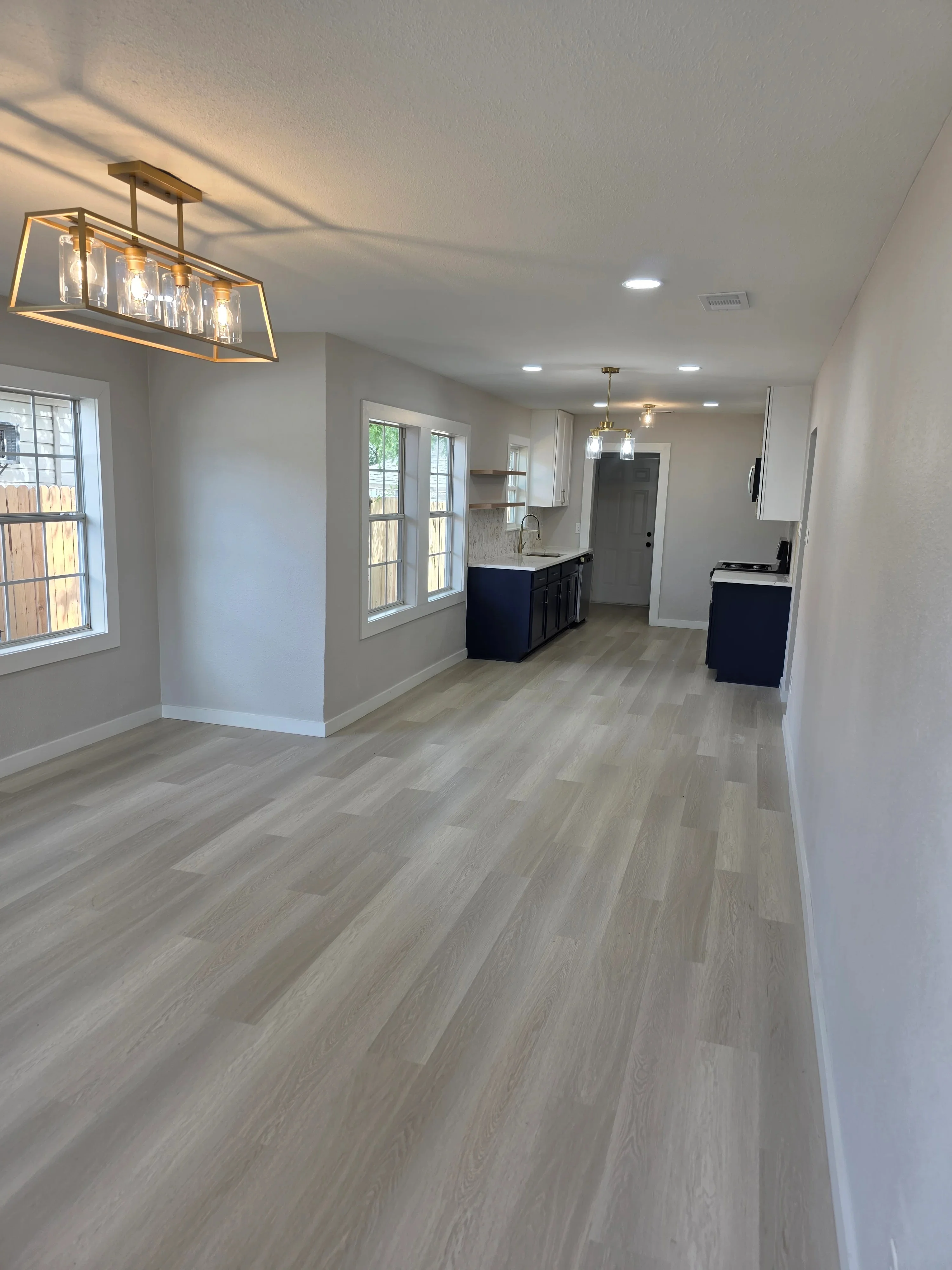 Modern kitchen with recessed LED lights, brass pendant fixture, and light wood flooring