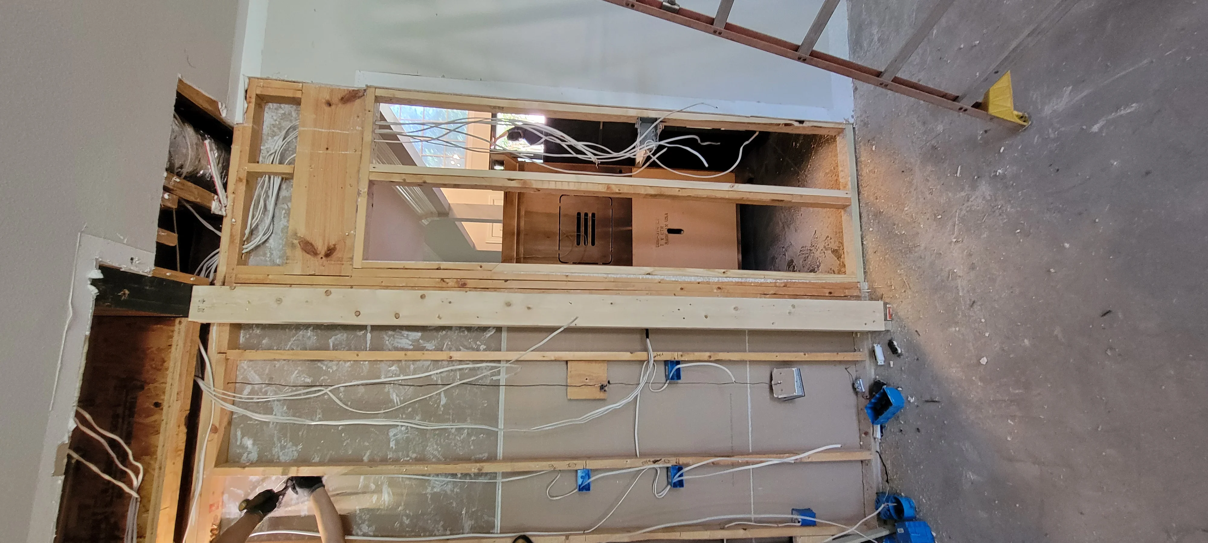 Electrical rough-in with white conduit, blue connectors, and outlet boxes in wooden stud framing