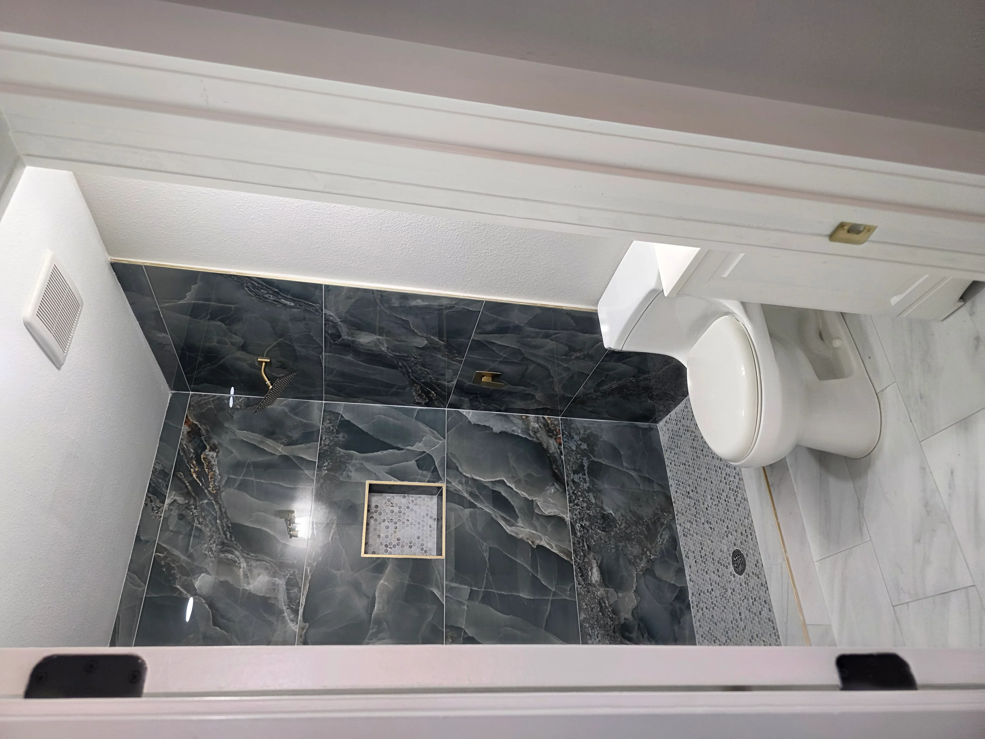 Bathroom with black marble tile shower, heated floor system, recessed lighting, and brass fixtures